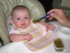 Baby eating baby food (blended green beans)