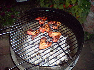 Chicken wings being cooked slowly over charcoa...