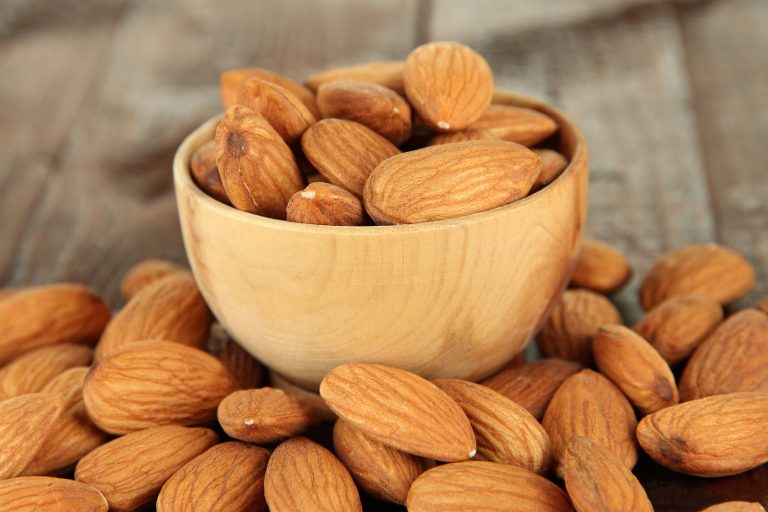 Almond in wooden bowl, on wooden background