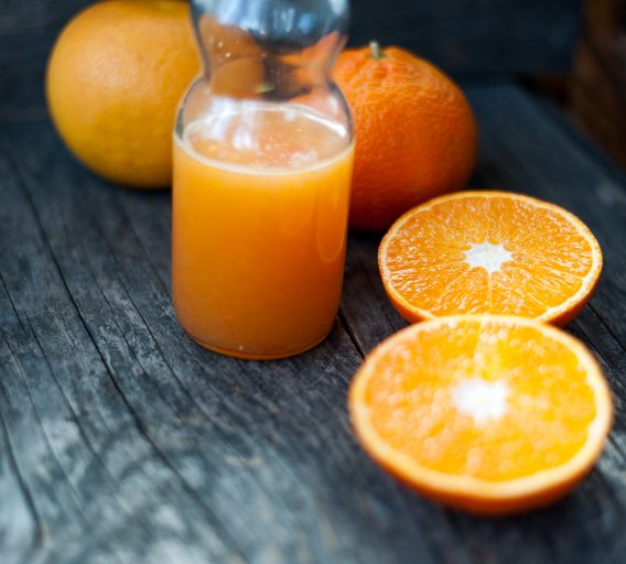 Fresh orange juice and fresh oranges on a wooden table