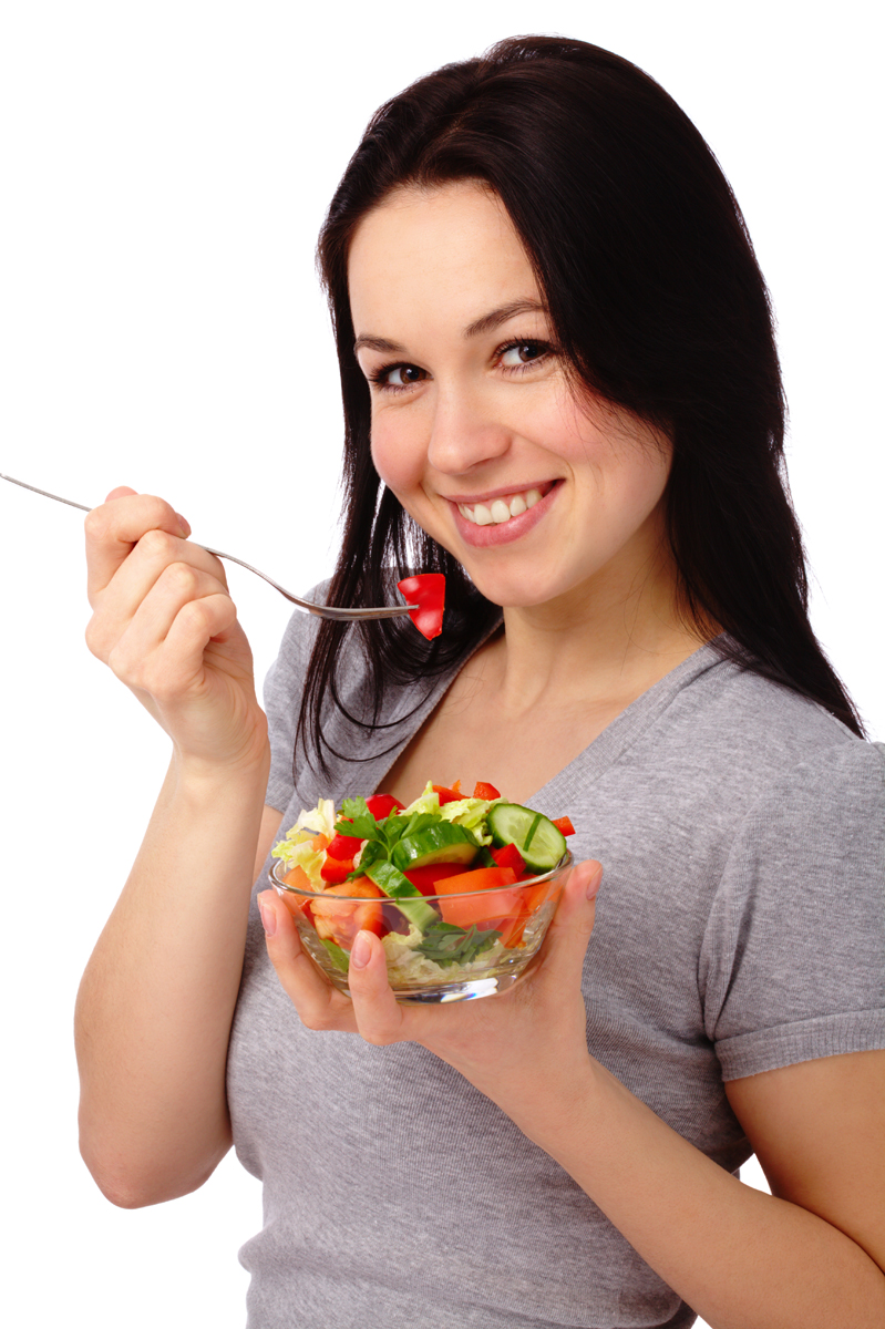 Young attractive woman eats vegetable salad using fork, isolated over white