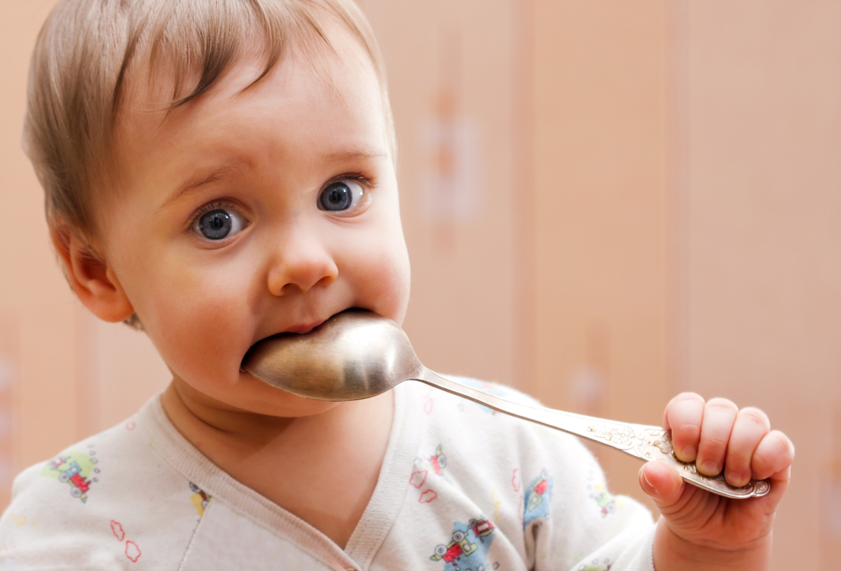 Portrait of baby girl holding spoon in mouth