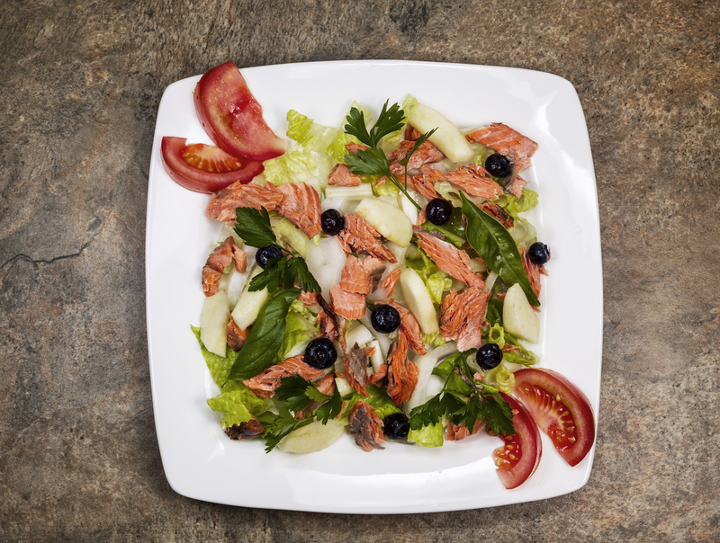 Red Salmon Salad with fresh garden tomatoes, basil, parsley, lettuce, onion, pears on white plate
